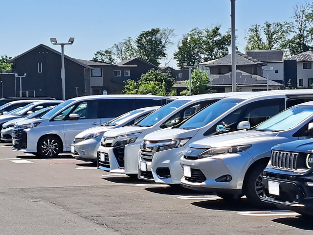 青空の下、たくさんの車が止まっている平面駐車場